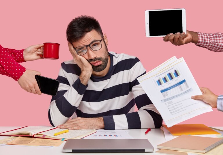 Homme fatigué et débordé entouré de tâches multiples, symbolisant la surcharge de travail et le stress.