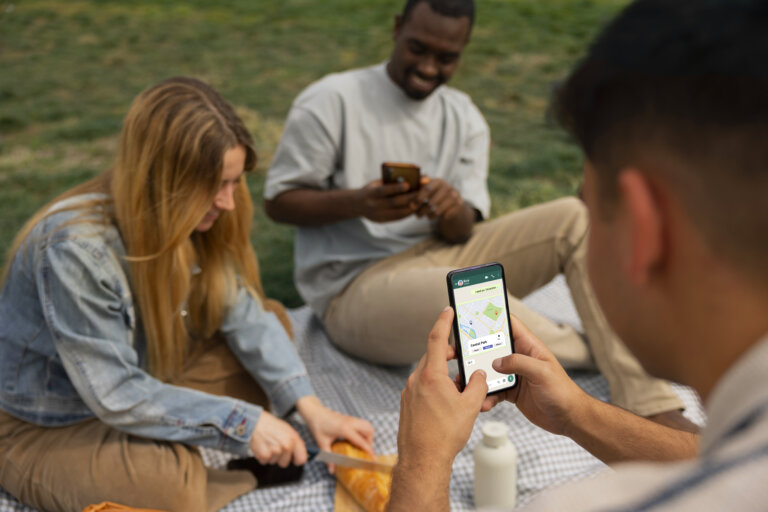 Trois personnes utilisant des smartphones en extérieur, illustrant l'interaction numérique via une application.